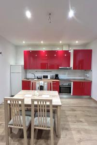 uma cozinha com armários vermelhos e uma mesa e cadeiras de madeira em Centric 1ºD em Madri
