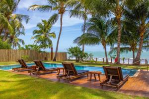 uma piscina com cadeiras e uma mesa junto ao oceano em Pousada Vila Cobé em Japaratinga