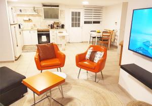 sala de estar con sillas de color naranja y TV de pantalla plana en Spacious and Peaceful 2BD with a Garden & Parking en Gan H̱ayyim