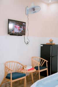 Zimmer mit 2 Stühlen und einem TV an der Wand in der Unterkunft Calido Hotel Vung Tau in Xã Thang Tam