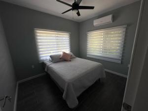 a bedroom with a bed with a fan and two windows at Baquis Island Bungalow in Utila