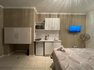 1 dormitorio con 1 cama, escritorio y TV en DOMIN LUXURY SUITES en Ciudad del Cabo