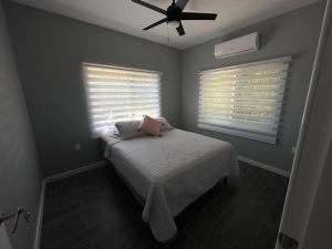 a bedroom with a bed with a fan and two windows at Baquis Island Bungalow in Utila