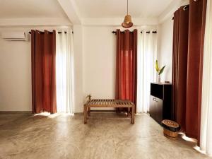 a living room with red curtains and a bench at Linton Villa in Kalutara