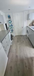 a white kitchen with a sink and a washing machine at 4 bedroom house opposite the sea in Kent