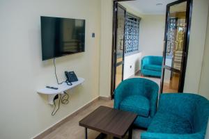 Habitación con 2 sillas, TV y mesa. en The Kolel Hotel and Suites en Eldoret