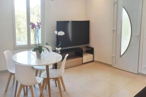 a dining room with a table and a tv at 2p bas de Villa avec Jacuzzi privatif proche de Nice in Saint-Laurent-du-Var