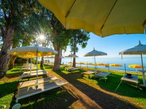 a row of benches with umbrellas on the beach at Hotel Eden Park Cilento in Policastro Bussentino