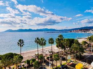 a view of a beach with palm trees and the ocean at Incroyables appartements dans une résidence de haut standing in Cannes