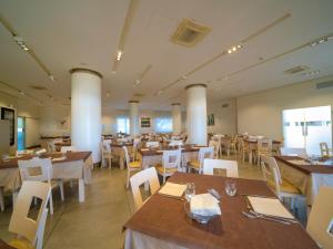 un restaurante con mesas de madera y sillas blancas en Hotel Eden Park Cilento, en Policastro Bussentino