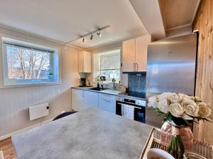 uma cozinha com uma mesa com um vaso de flores em Leknes Airport Apartment em Leknes