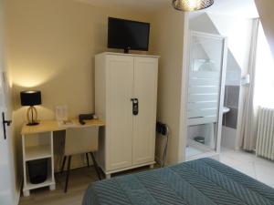 een slaapkamer met een bureau en een tv op een kast bij Hotel des Voyageurs in Payzac
