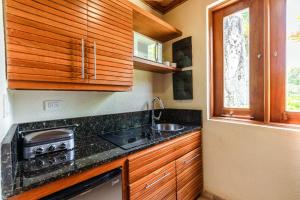 a kitchen with wooden cabinets and a sink and a stove at Newly added Tropical Bungalow at Green Village in Punta Cana
