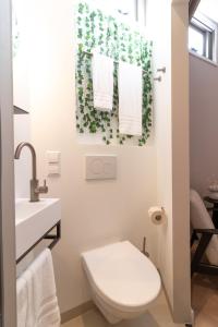 a white bathroom with a toilet and a sink at SAYŌ Boutique Hotel in Scheveningen