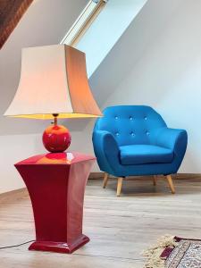 uma lâmpada sobre uma mesa ao lado de uma cadeira azul em LA FERME DE NEHOU em Gatteville-le-Phare