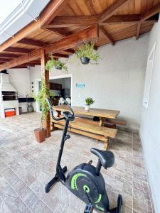 uma bicicleta de exercício numa sala com uma mesa em RJ Residencial Beira Mar Deliciosa Casa Frente Mar na Pinheira com piscina em Pinheira