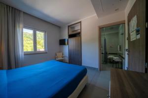 a bedroom with a blue bed and a bathroom at Hotel Eden Park Cilento in Policastro Bussentino