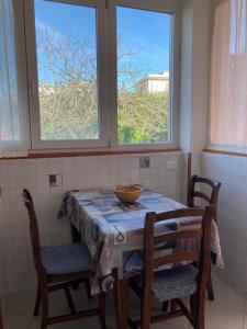 a table with chairs and a bowl on it in a room with two windows at Casa Rina in Livorno