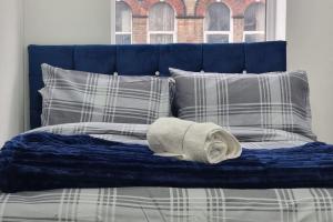 a blue bed with pillows and a towel on it at 2 Bed Cosy Flat close to Bus & Tube Station in London