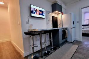 2 Bed Cosy Flat close to Bus & Tube Station في لندن: مطبخ مع كونتر مع تلفزيون على الحائط