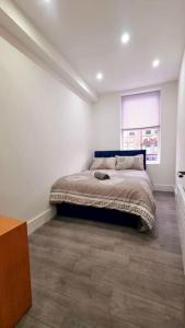 a bedroom with a bed in a white room at 2 Bed Cosy Flat close to Bus & Tube Station in London
