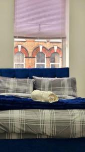 a bed with a blue head board and a window at 2 Bed Cosy Flat close to Bus & Tube Station in London