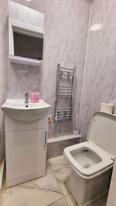 a white bathroom with a toilet and a sink at 2 Bed Cosy Flat close to Bus & Tube Station in London