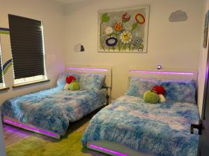 dos camas con animales de peluche sentados sobre ellas en un dormitorio en The Neon Nest: Retro Chic 4BR Home in Cooper Young, en Memphis