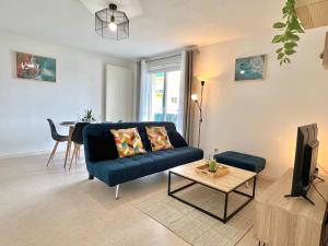 uma sala de estar com um sofá azul e uma mesa em Le Nirvana ~ Jolie t2 avec Balcon / 2 min du parc em Jaunay-Clan
