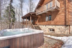 bañera de hidromasaje grande frente a una cabaña de madera en Chalet Zurri en Labelle