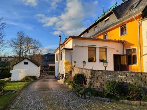 a yellow and white house on a cobblestone street at Gasthof Blankenberg 