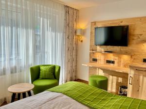 バート・ハルツブルクにあるHotel Tannenhofの緑の椅子とテレビが備わるホテルルームです。