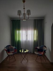 ein Wohnzimmer mit 2 Stühlen, einem Tisch und einem Kronleuchter in der Unterkunft Quinta das Laranjeiras in Marinhais