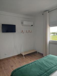 ein Schlafzimmer mit einem grünen Bett und einem TV in der Unterkunft Quinta das Laranjeiras in Marinhais