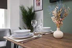 a wooden table with plates and wine glasses on it at Central 2 bedroom flat in the heart of the lanes in Brighton & Hove