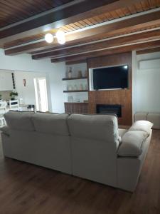 ein Wohnzimmer mit einem weißen Sofa und einem TV in der Unterkunft Quinta das Laranjeiras in Marinhais
