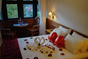 a hotel room with a bed with two heart shaped pillows at Campos Hotel do Sol in Campos do Jordão