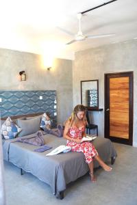 a girl sitting on a bed reading a book at Rasdu View Inn in Rasdhoo