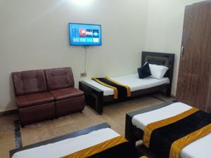 a room with two beds and a couch and a tv at Second Home Family Hotel in Lahore +43 photos