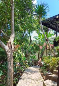 une passerelle traversant un jardin avec un palmier dans l'établissement Kraras Munduk Guest House & DonBiyu Rendezvous Restaurant, à Munduk
