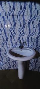 a white sink in a bathroom with blue and white tiles at Petit Hollande guest rooms in Abémé