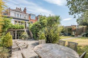 a patio with a wooden table and chairs in front of a house at Tower House, Cowes Old Town in Cowes