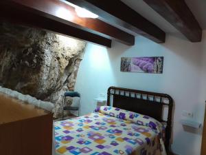 a bedroom with a bed in front of a stone wall at Casa Manolita in Puebla de Benifasar