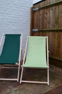 two lawn chairs sitting next to a fence at Cozy Town House in Lewes