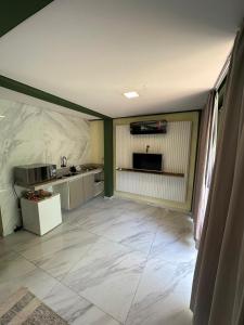 uma grande cozinha com paredes de mármore branco e um balcão em Hospedagem para família em Palhoça