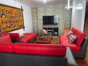 salon z czerwonymi kanapami i telewizorem w obiekcie Casa Hospedaje “YURAQ WASI” w mieście Huaraz