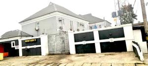 a white house with two garage doors and a fence at Rocket Room Hotel & Suites Limited in Port Harcourt