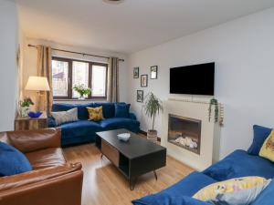 a living room with blue couches and a tv at Sylvannah in Buxton