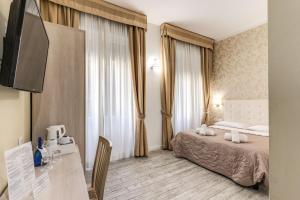 Cette chambre comprend un lit, un bureau et une fenêtre. dans l'établissement Gardenia Suite, à Rome