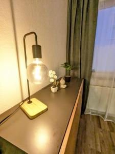 a desk with a lamp and flowers on it at Wohnung nahe Messe und Zentrum in Nuremberg